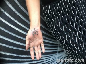 Фото тату: изящная татуировка солнца на ладони, выполненная в тонких черных линиях. Символ энергии и жизни.