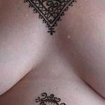 Фото татуировки на груди женщины с изображением сложного кружевного узора в черном цвете.