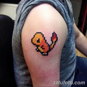 Фото тату пиксельного Чармандера из Pokemon на плече. Яркий и узнаваемый рисунок в стиле 8-bit, выполненный в оранжевых и черных тонах.
