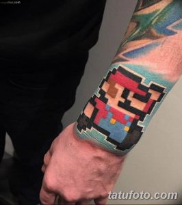 Фото татуировки в стиле пиксель-арт с изображением Марио из игры Super Mario Bros. на руке. Яркие цвета и четкие линии.