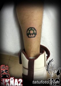 Фото тату с изображением пиксельного гриба из Super Mario на лодыжке. Небольшой и яркий рисунок в стиле 8-bit.