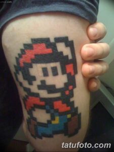 Фото татуировки на руке, изображающей пиксельного Марио из игры Super Mario Bros., выполненного в ярких и насыщенных цветах.