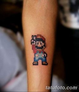 Фото тату: пиксельный Марио из игры Super Mario на предплечье. Яркие цвета и узнаваемый стиль 8-bit делают эту татуировку идеальной для поклонников ретро-игр.