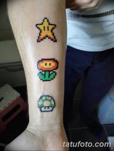 Фото татуировок в пиксельном стиле: звезда, гриб и цветок из Super Mario Bros. на руке. Яркие цвета и четкие пиксели.