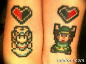 Фото тату: пиксельные сердца и маска из The Legend of Zelda на запястье. Оригинальный дизайн для фанатов видеоигр и романтиков.