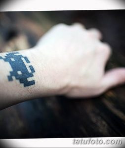 Фото тату: пиксельный синий дракон на запястье. Рисунок выполнен в стиле 8-bit, имитируя старые видеоигры. Простой, но эффектный дизайн.