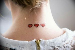 Фото тату с изображением трех пиксельных сердец, выполненных в красных тонах на шее.