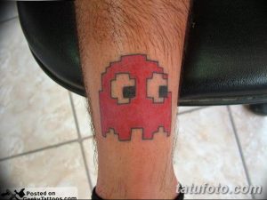 Фото татуировки в стиле пиксель-арт с изображением красного призрака из игры Pac-Man на ноге.