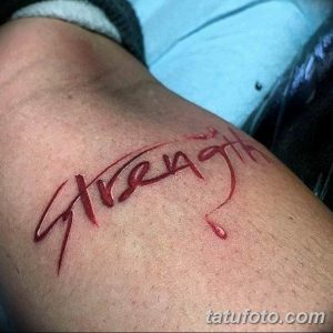 Фото тату надписи 'Strength' выполненной красными чернилами на предплечье. Стиль - леттеринг, с эффектом капающей крови.
