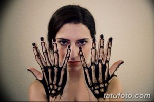 Фото тату: креативная татуировка скелета рук, расположенных по обе стороны лица, создающая эффект маски.