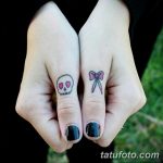 Фото тату двух маленьких татуировок на пальцах: черепа с розовыми сердечками и бантика. Нежный и оригинальный дизайн.
