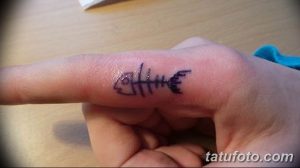 Фото тату абстрактного рисунка на пальце руки. Черные линии и символы создают загадочный и оригинальный образ.