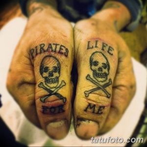 Фото тату на пальцах: два черепа с костями и надписи 'Pirates for life'. Небольшие татуировки в минималистичном стиле.