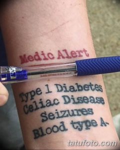 Фото тату на предплечье: надпись 'Medic Alert' и информация о заболеваниях и группе крови. Черно-красная цветовая гамма и информативный дизайн.