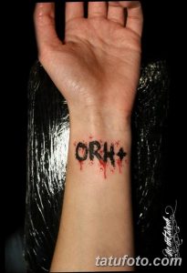 Фото тату на запястье: надпись 'ORH+' с капающей кровью. Черно-красная цветовая гамма и простой дизайн.
