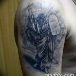 Фото тату: реалистичный рисунок Моисея с каменными скрижалями на плече, выполненный в черно-серых тонах. Эскиз татуировки в религиозном стиле.
