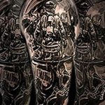 Фото тату с изображением сложной композиции, включающей горящее здание и пожарных, выполненное в черно-белом стиле на руке.