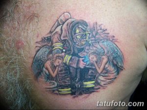 Фото татуировки на груди: пожарный в форме держит на руках двух маленьких ангелов. Черно-белая графика с элементами цветных акцентов.