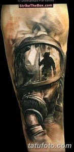 Фото тату на руке с изображением пожарного в шлеме, в котором виден силуэт пожарного. Детализированный черно-серый рисунок татуировки.