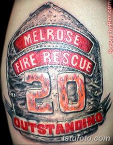 Фото тату на руке с изображением пожарного шлема с надписью 'Melrose Fire Rescue 20 Outstanding'. Детализированный рисунок татуировки.