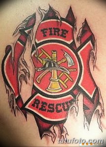 Фото тату пожарного знака с изображением топора и надписями 'FIRE' и 'RESCUE'. Цветной рисунок татуировки на груди, символизирующий службу спасения.