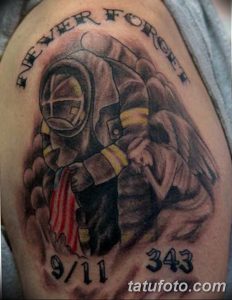 Фото тату пожарного с надписью 'Never Forget 9/11' и цифрами '343' на плече. Патриотичный рисунок татуировки в память о трагедии.