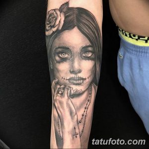 Фото тату: черно-белая татуировка в стиле Sugar Skull с изображением девушки, украшенной цветами и четками, на предплечье.