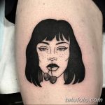 Фото тату на бедре: минималистичная татуировка с изображением девушки с черными волосами и вишнями в губах, выполненная в черном цвете.