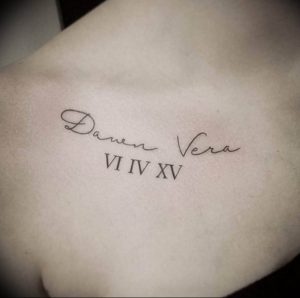 Фото тату: черная татуировка с именем 'Daven Vera' и римскими цифрами 'VI IV XV' на ключице. Персонализированный и элегантный дизайн.