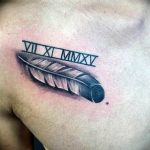 Фото тату: реалистичное изображение пера с римскими цифрами 'VII XI MMXV' над ним на мужской груди. Стильный и символичный дизайн.
