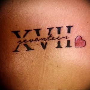 Фото тату: черные римские цифры 'XVII' и изображение сердца на спине. Простой и символичный дизайн, выражающий любовь и привязанность.