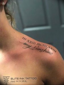 Фото тату: черные римские цифры и надпись 'my sunshine' изящно расположены на ключице. Красивый и личный дизайн, выполненный каллиграфическим шрифтом.