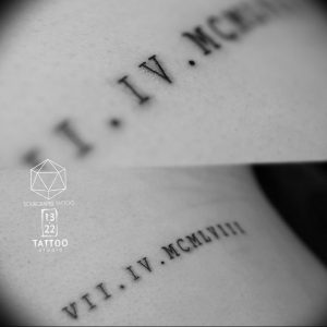 Фото тату: крупный план татуировки с римскими цифрами 'I.IV.MCM', минималистичный дизайн, тонкие линии, рисунок татуировки.