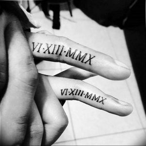 Фото парных татуировок на пальцах с римскими цифрами VI-XIII-MMX. Черно-белый рисунок, минималистичный дизайн, символ даты и любви.