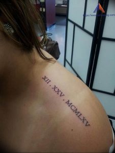 Фотография татуировки на плече с римскими цифрами "XII. XXV. MCMLXV", выполненной черным цветом.