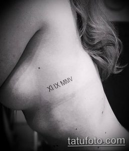 Фотография женской татуировки на боку с римскими цифрами "XI IX MMV", выполненной тонкой линией.