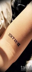 Фото тату: черные римские цифры 'XIX.T.IA.IX' на предплечье. Минималистичный дизайн, четкие линии, подходит для тех, кто ценит лаконичность.