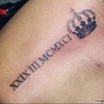 Фото тату: черные римские цифры 'XXIX.III.MCMXCI' и небольшая корона на плече. Символизирует власть, величие и значимую дату.