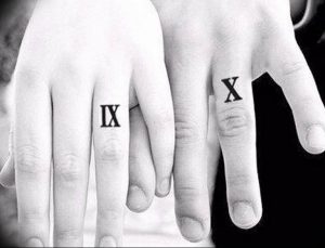 Фото тату: Пара с минималистичными татуировками римскими цифрами IX и X на безымянных пальцах. Черный контур, нежная композиция.