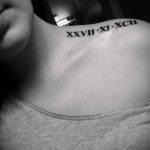 Фото тату на ключице: длинная горизонтальная линия римских цифр, выполненная черным цветом, символизирующая важные даты.