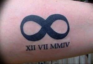 Фото тату с символом бесконечности и римскими цифрами XII VII MMIV на руке. Черный рисунок татуировки выглядит минималистично и символично.