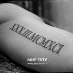 Фото тату с римскими цифрами XXX.III.MCMXCI на руке. Черный рисунок татуировки выполнен аккуратным шрифтом, выглядит стильно и минималистично.