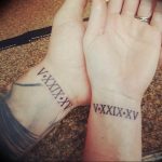 Фото парных татуировок на запястьях с римскими цифрами 'V.XXIX.XV'. Минималистичный дизайн для любящих пар.