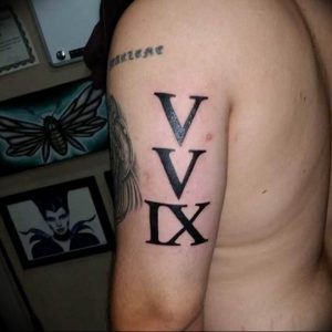 Фото тату: черная татуировка с римскими цифрами 'V V IX' на плече. Простой и стильный рисунок татуировки.