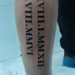 Фото тату: Длинная вертикальная татуировка с римскими цифрами, расположенная на икре. Элегантный и стильный дизайн.