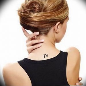 Фото тату на затылке девушки: маленькая римская цифра IV, выполненная черными чернилами. Простой и элегантный дизайн.