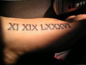 Фото тату: черные римские цифры 'XI XIX XIX LXXXV LXXV' на запястье, выполненные в строгом стиле.