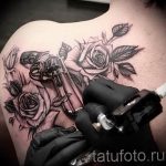 Фото тату револьвера, окруженного розами на плече. Детализированный рисунок оружия и цветов в черно-белых тонах. Красивый эскиз тату для девушек и мужчин.