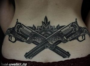 Фото тату двух револьверов, перекрещенных с мандалой на спине. Детализированный рисунок в стиле blackwork. Оригинальный эскиз тату для девушек.