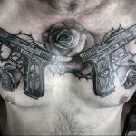 Фото тату: два пистолета, обвитых розами, на груди мужчины. Мощный и символичный рисунок, выполненный в черно-белой гамме.